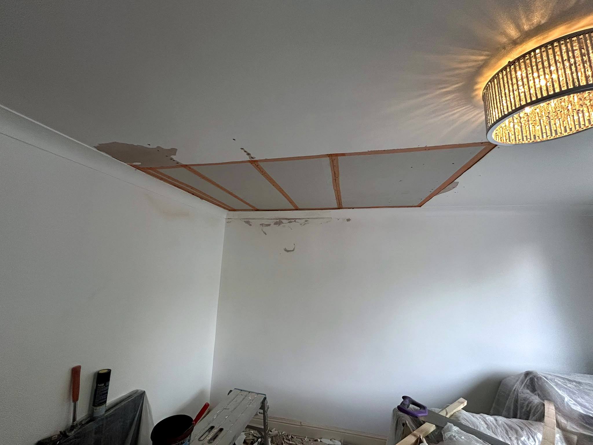 Damaged section of a living-room ceiling cut out and boarded