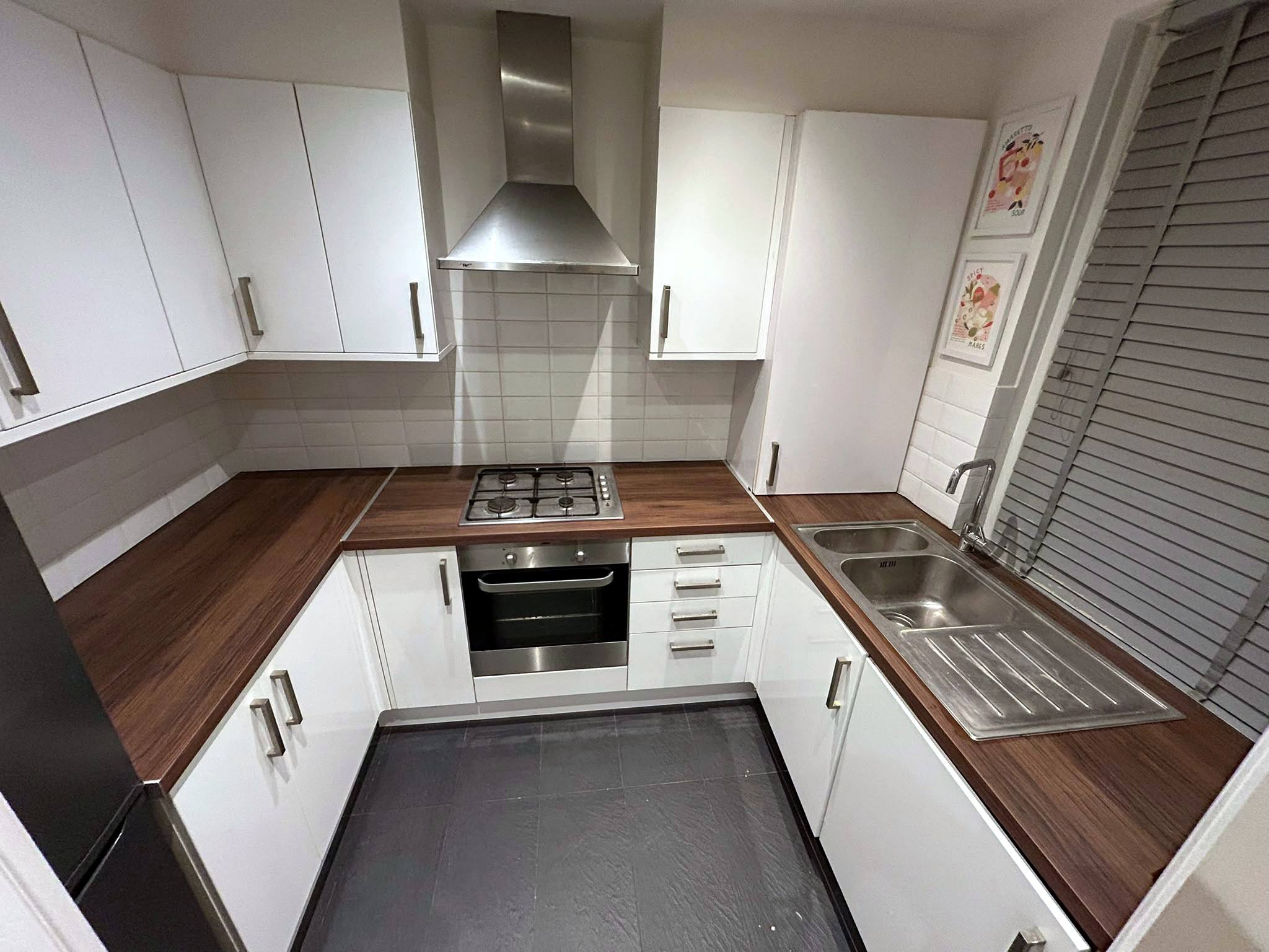 U-shaped kitchen with white units and wood-effect worktops