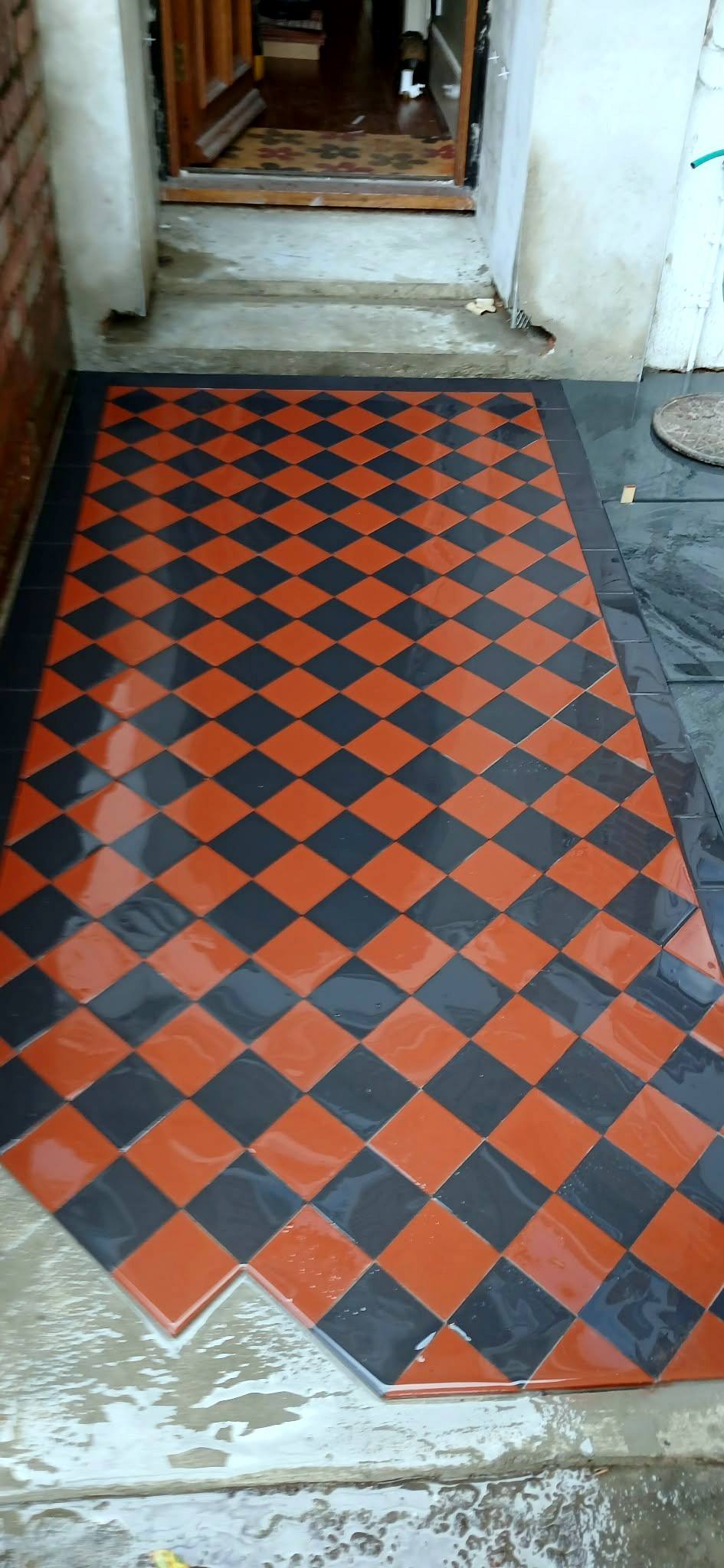 Red and black tiled path to a front door